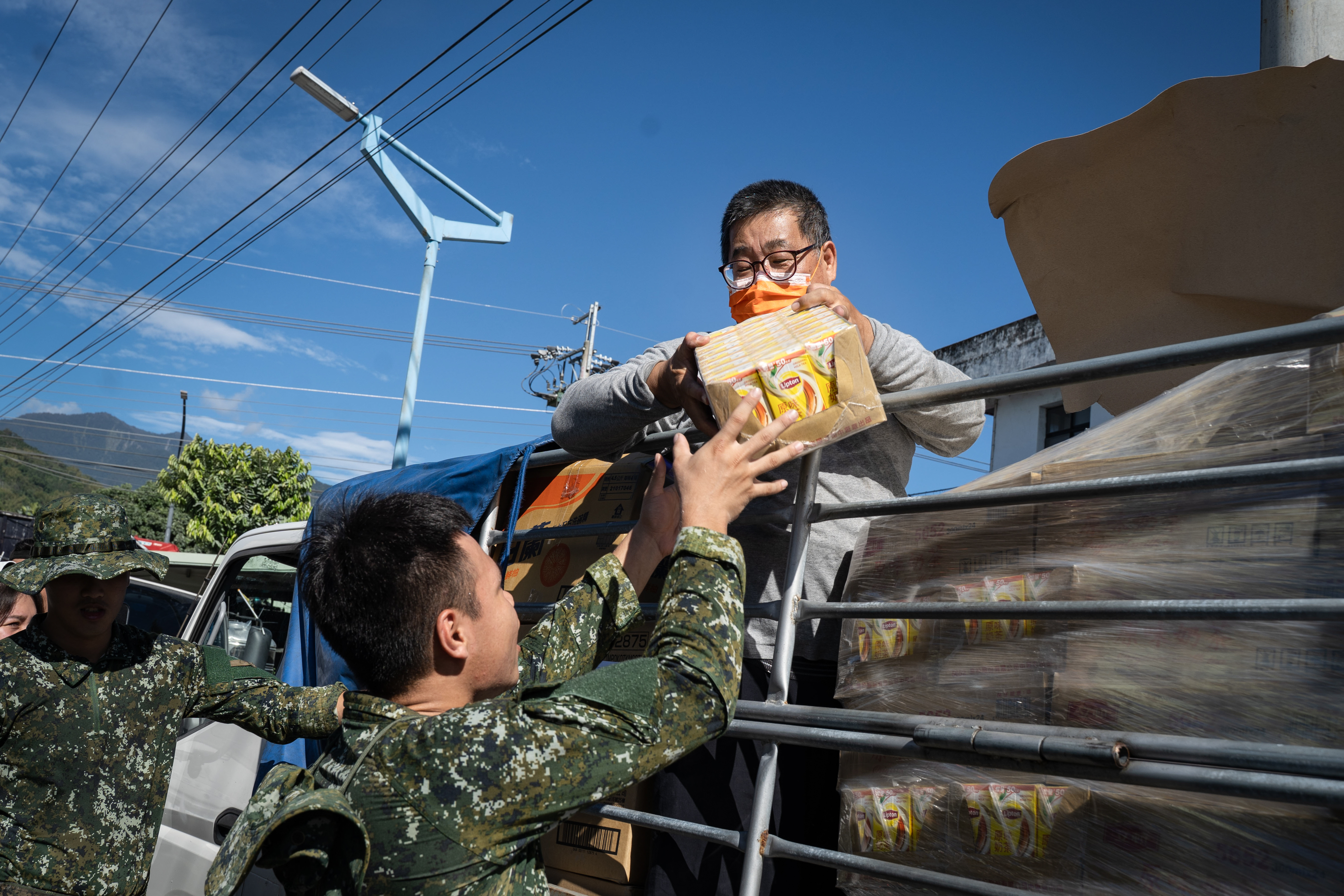 好人會館創辦人黃榮墩（圖右）頂著椎間盤突出的舊疾與腰痛，來回往返災區協助災民，也專程致贈飲料感謝前來協助的國軍弟兄們。（攝影／唐佐欣）