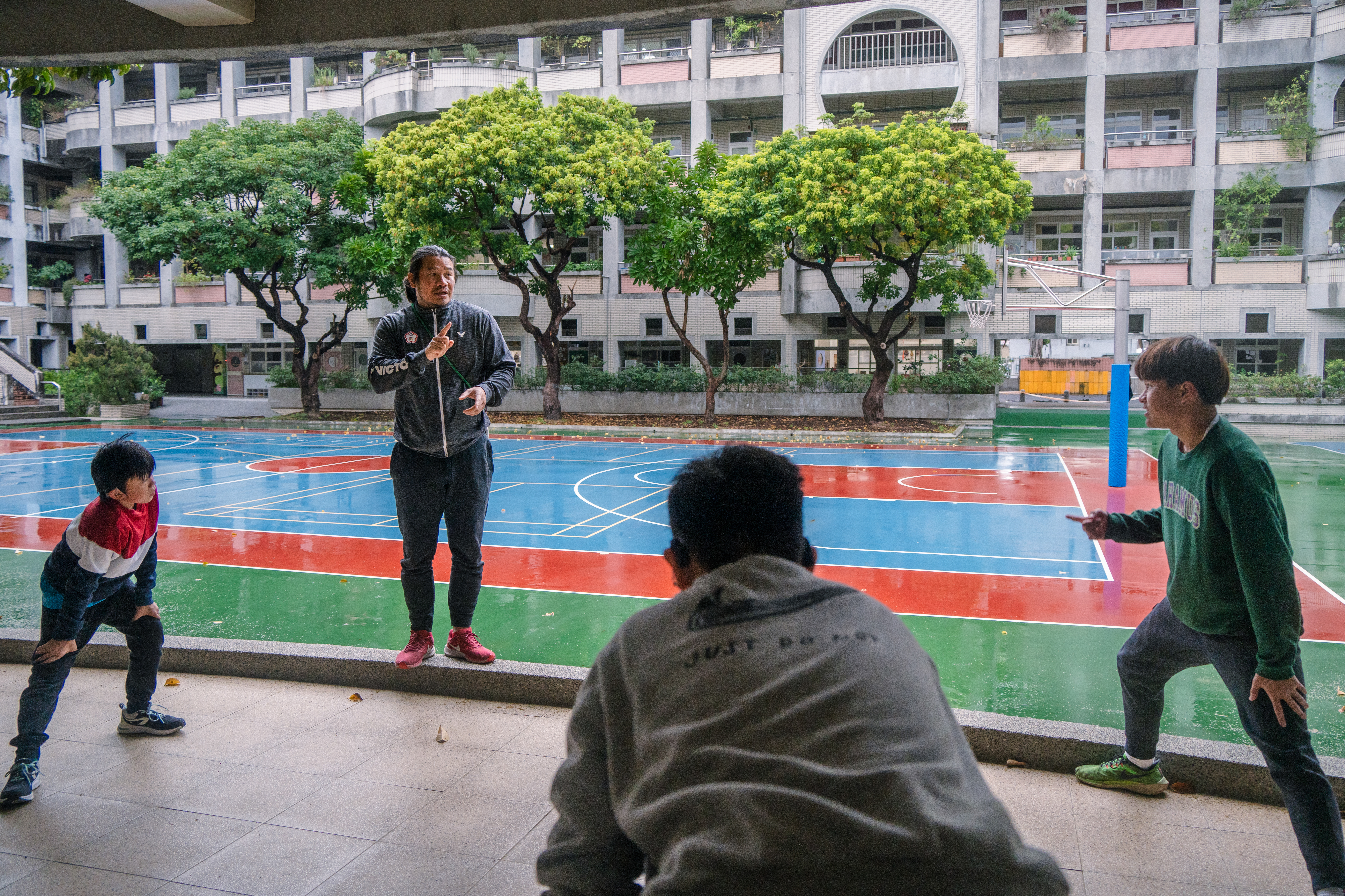 台北啟聰學校田徑隊每天在放學後集訓,安慶隆一邊帶著同學做熱身,一邊用手語與他們交談。(攝影/王崴漢)
