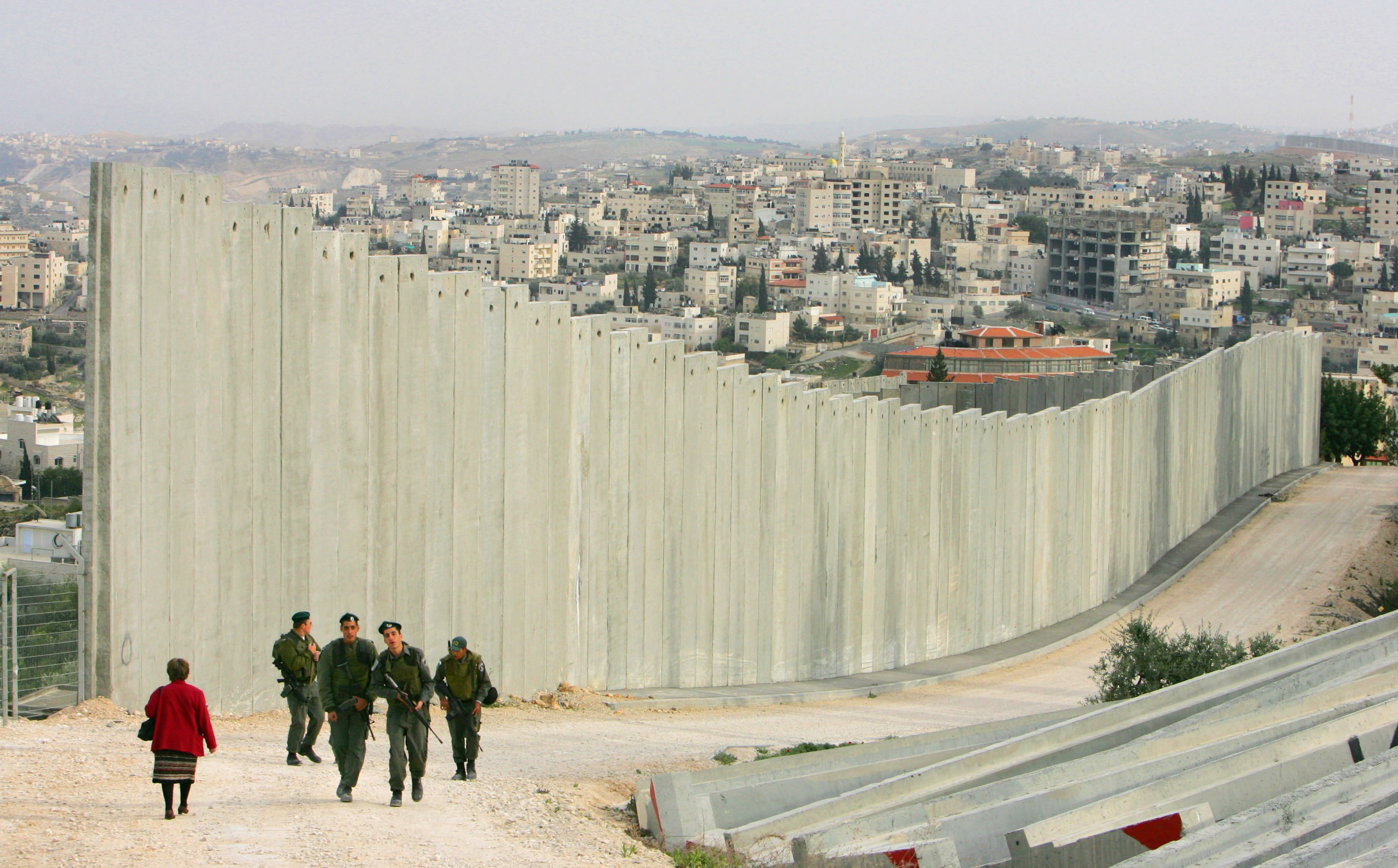 In March 2006, Israeli soldiers patrolled along the concrete barrier wall that separates East Jerusalem in Israel from the West Bank of the Jordan River. (Photographed by Paula Bronstein / Getty Images)