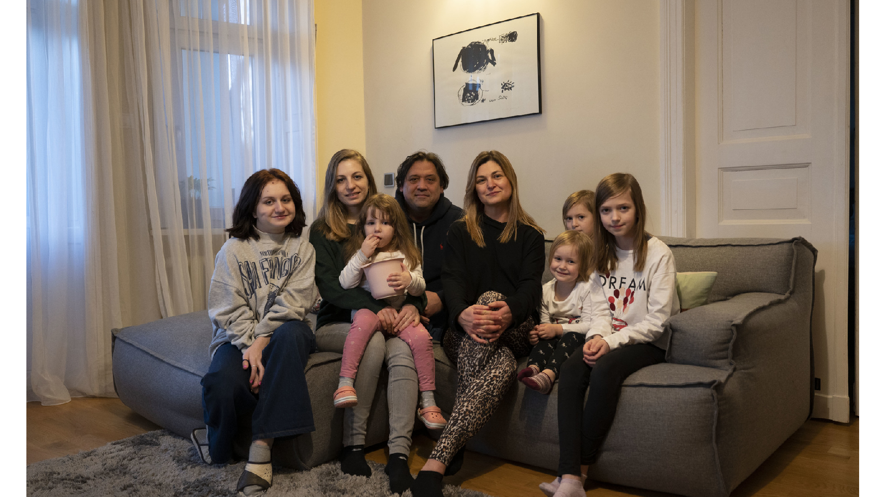 波蘭的法比安（Monika Fabjan，右4）與來自烏克蘭的漢娜（Hanna，左2）兩家人，在法比安住家的客廳裡合影。戰爭爆發後，許多波蘭家庭決定打開家門接待逃難的烏克蘭家庭。（攝影／楊子磊）