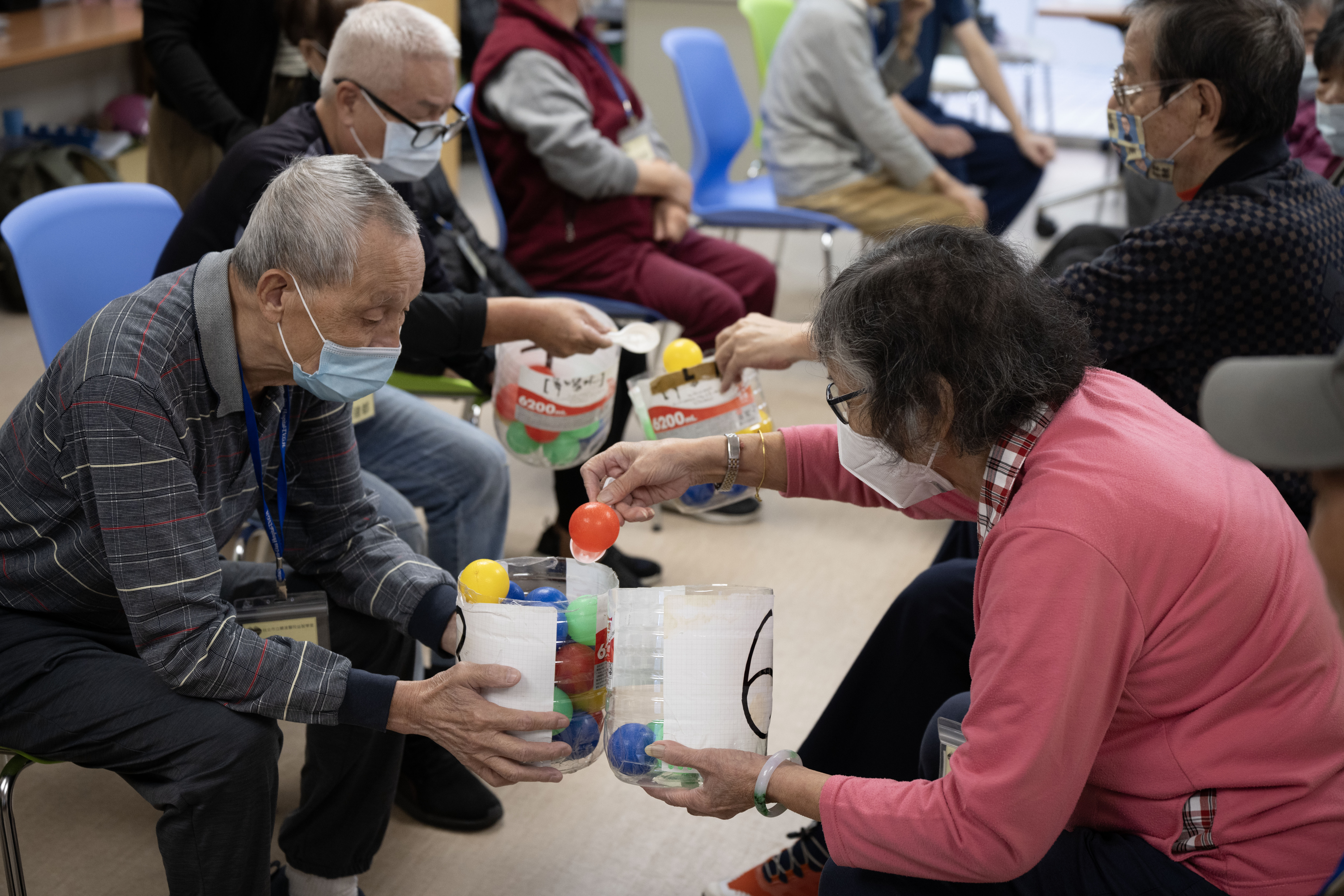 關渡醫院益智學堂的學員們，在老師的引導下透過傳遞物品訓練手部的協調感。（攝影／楊子磊）