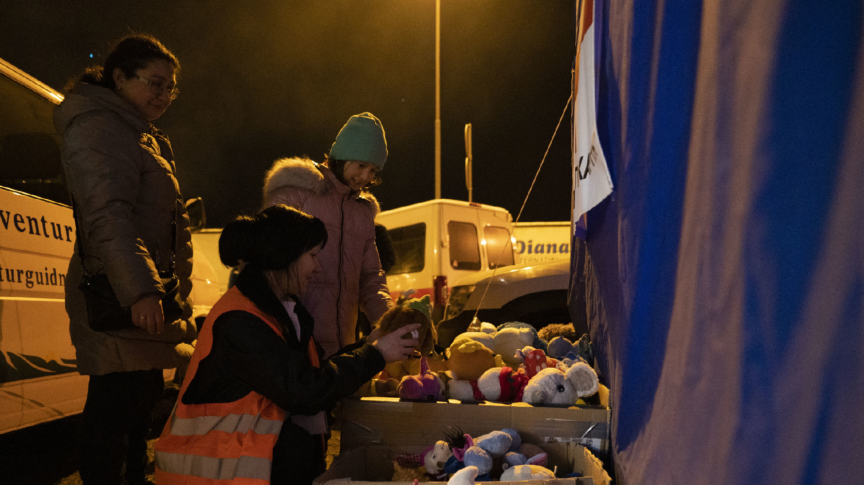 在波蘭東部接近烏克蘭邊界的公路旁，來自世界各地的志工準備了各種物資與食物，讓方才抵達的烏克蘭家庭能夠在此歇息。3月13日晚間，一位烏克蘭女孩在志工的協助下挑選自己喜歡的布偶。（攝影／楊子磊）