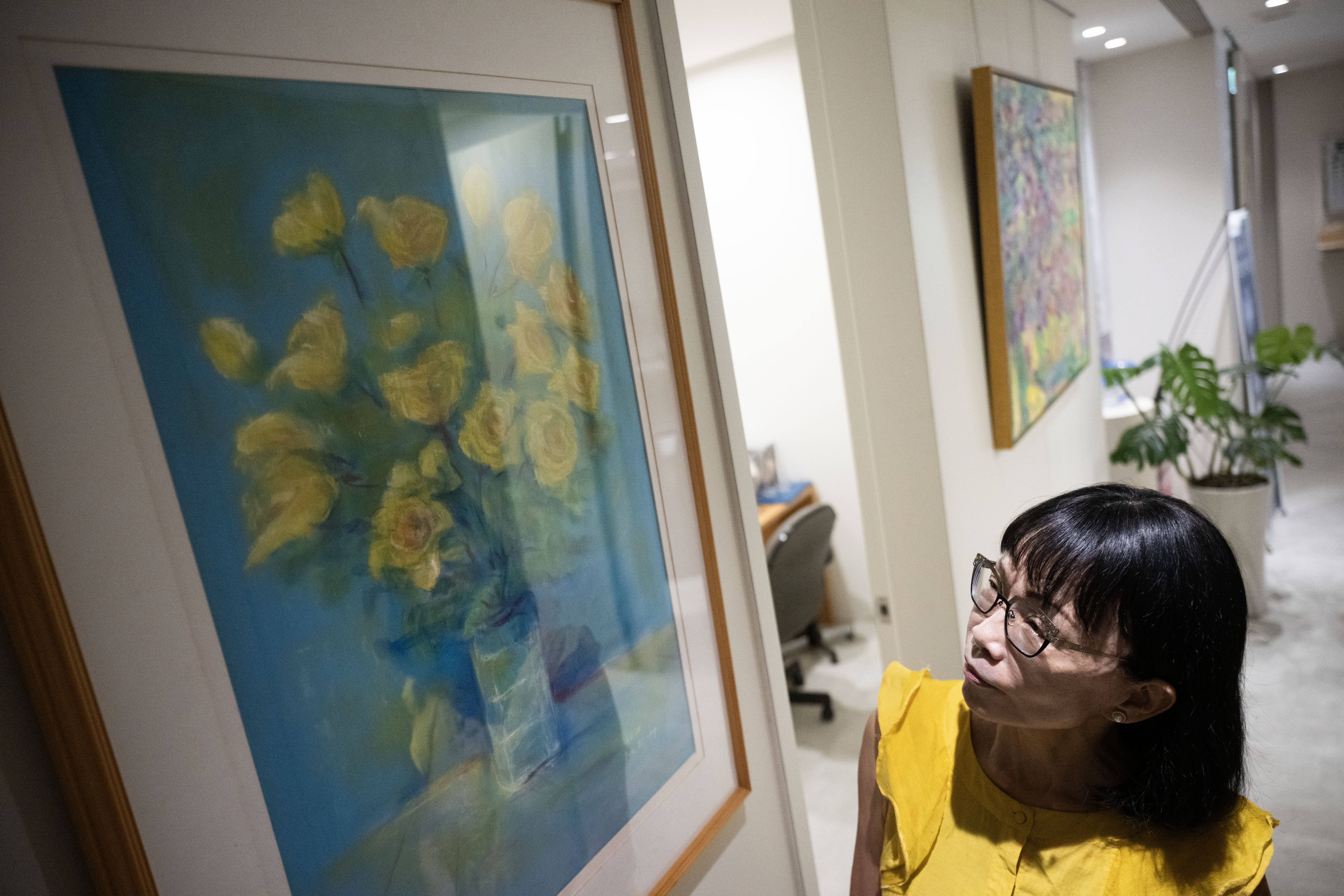 有了阿迪與旅長的幫忙，林靜芸成為照顧第二線，得以回到診所開刀、看診。她望著牆上父親林秋江醫師的畫作，在照顧者與醫師之間，繼續生活與工作。（攝影／楊子磊）