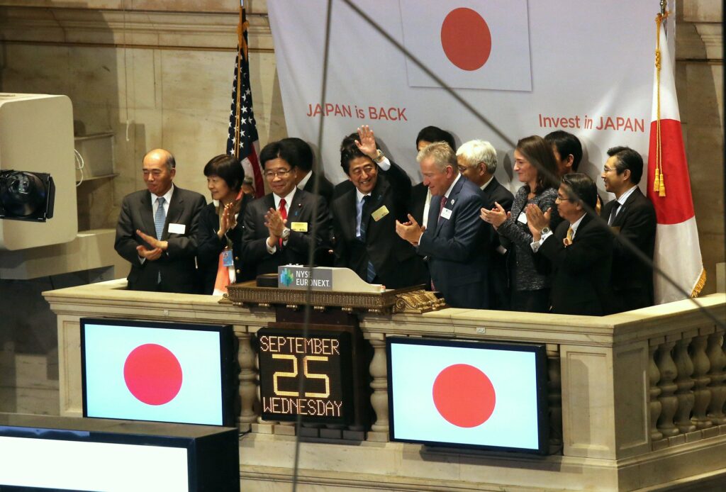 2013年9月25日，日本前首相安倍晉三於紐約證交所以「安倍經濟學」為主題發表演說，呼籲外商投資經濟復甦的日本。其身後的掛布寫著「日本回來了」、「投資日本」字樣。（攝影／Getty Images／John Moore）