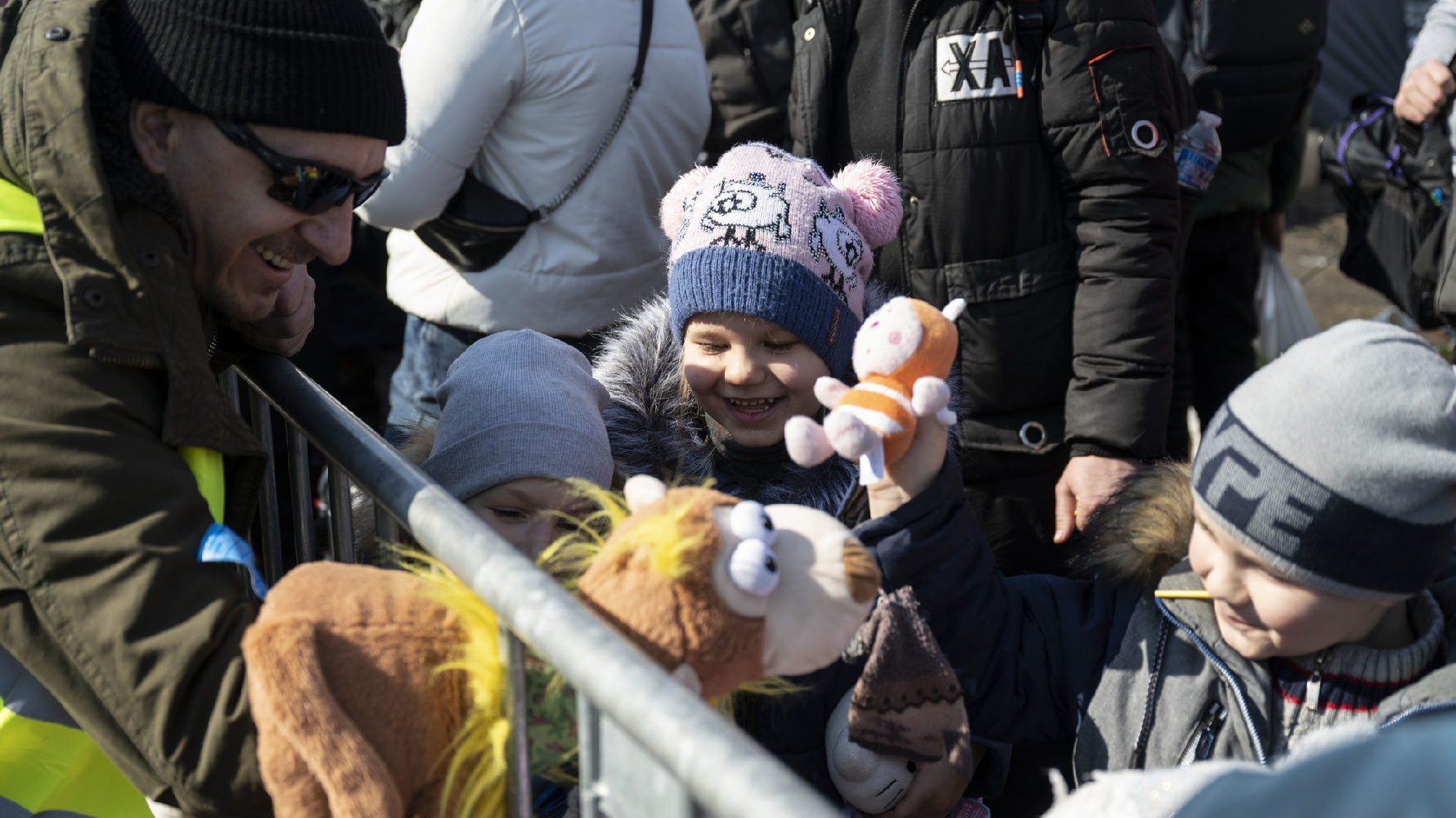 在波蘭邊境的梅迪卡，許多烏克蘭的民眾在此等待巴士，一個志工與等候搭車的隊伍中的孩子玩耍。（攝影／楊子磊）