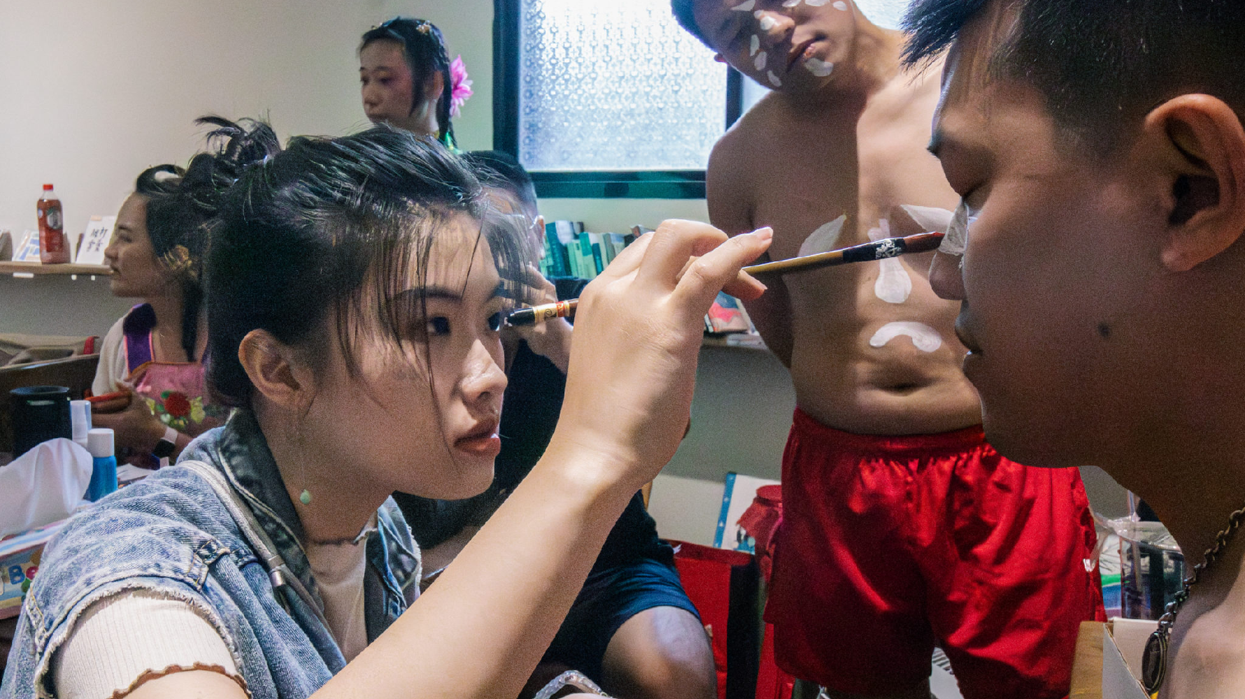 王丞瀞接下外公馬根壽化妝師的工作，為打花草的團員們上妝。（攝影／蔡亦閔）