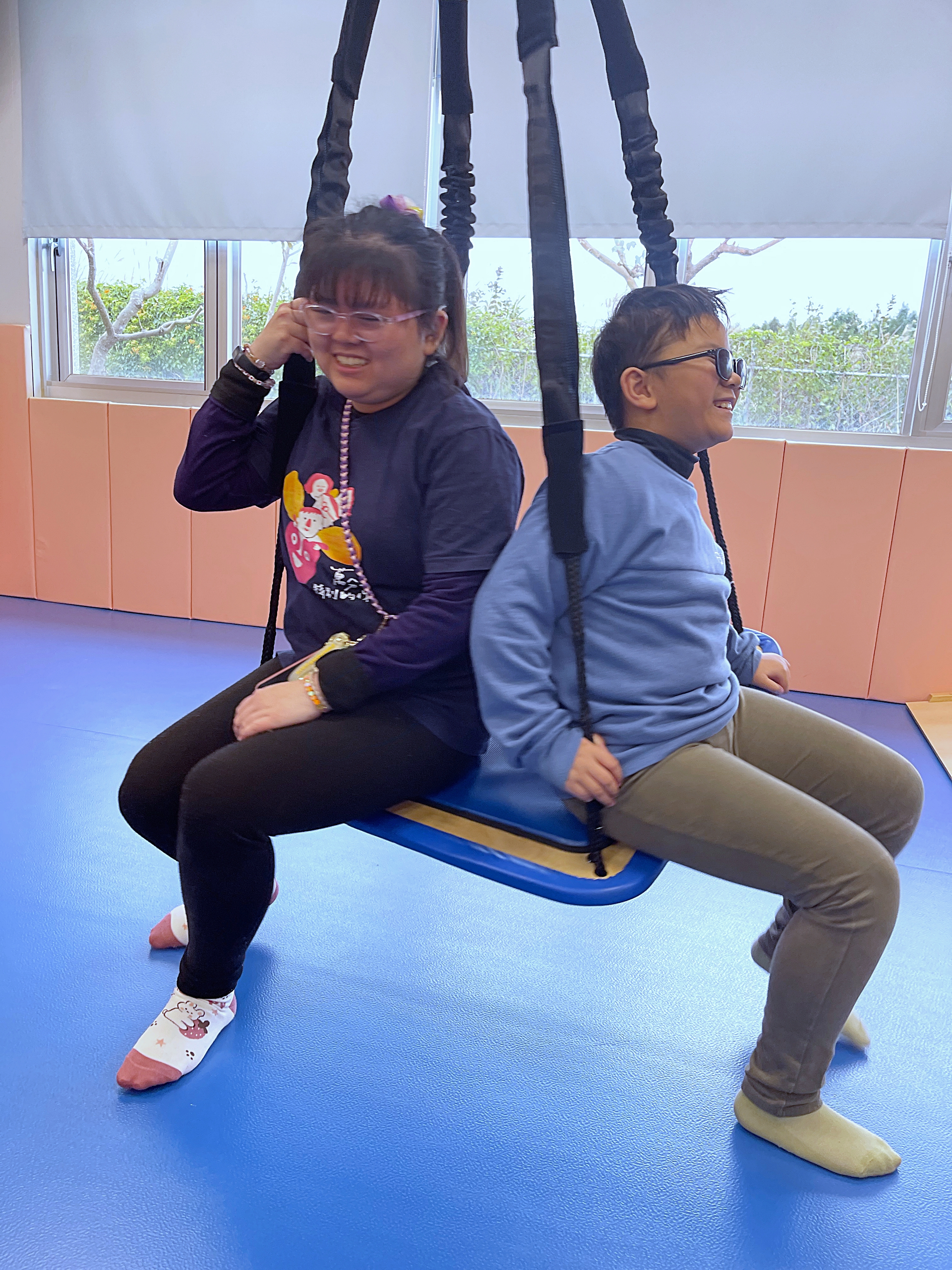 或許對拍攝地點感覺統合教室有熟悉感，渝軒和守恆坐在輔具上，顯得開心與放鬆。（攝影／李奕霈）