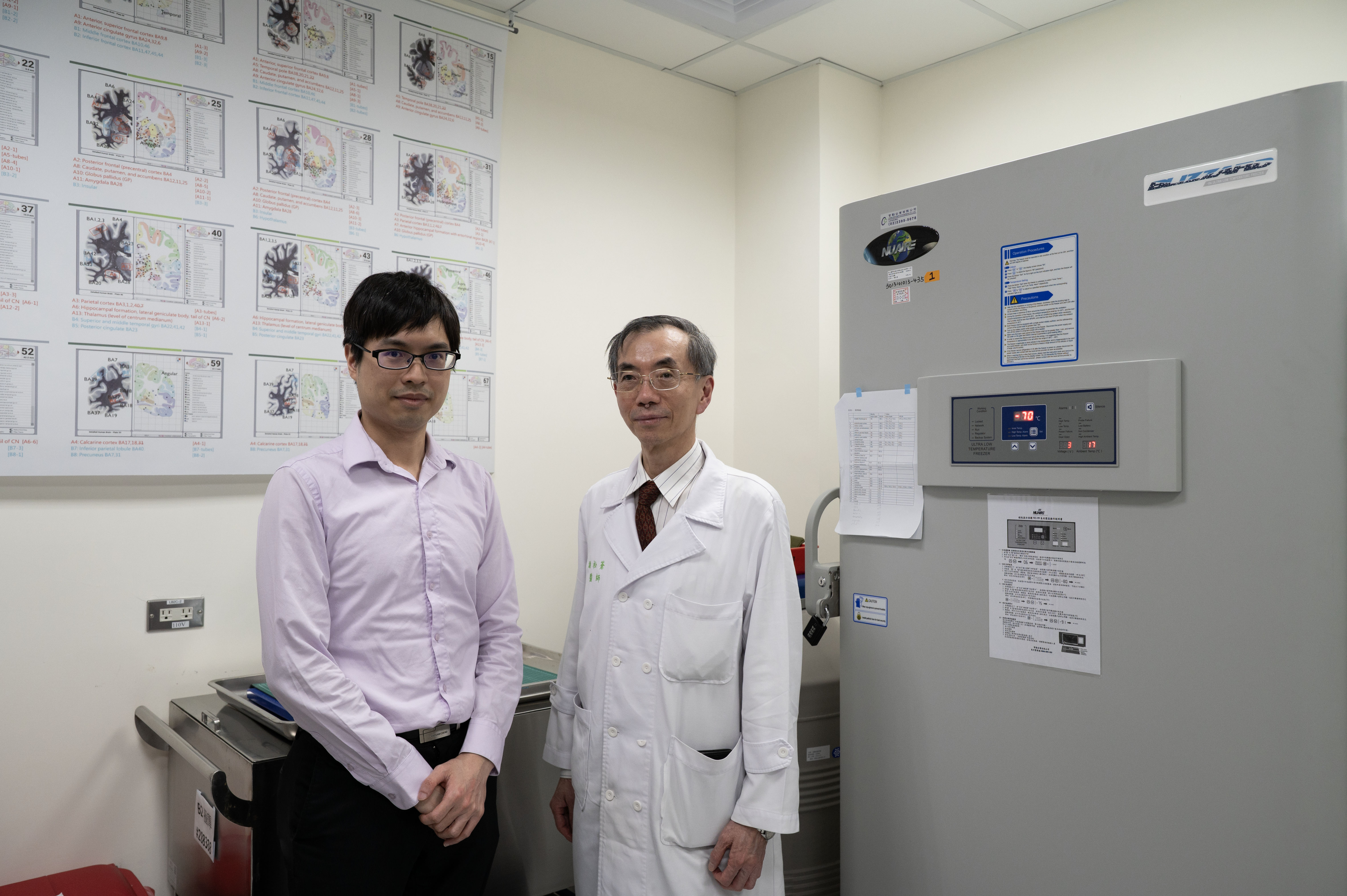 一通電話，謝松蒼（右）、張克平等腦庫成員便立即進入待命，準備承接病友捐出大腦的託付。圖中的冰箱冰凍著大腦，牆上的大腦分區圖，對應著不同的大腦功能。（攝影／楊子磊）