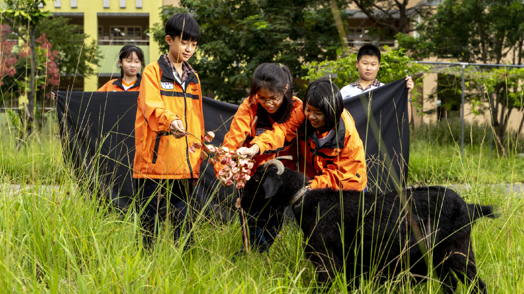 學生們拿著黑嚕嚕喜歡的食物，引牠一起來合照。（攝影／張家瑋）